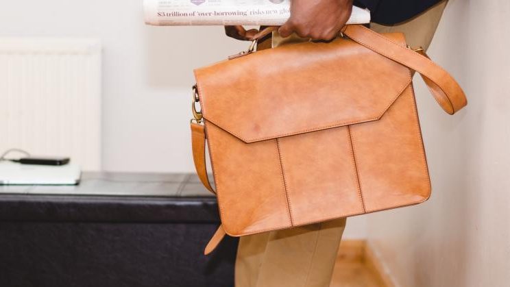 Person holding an orange briefcase in one hand. 